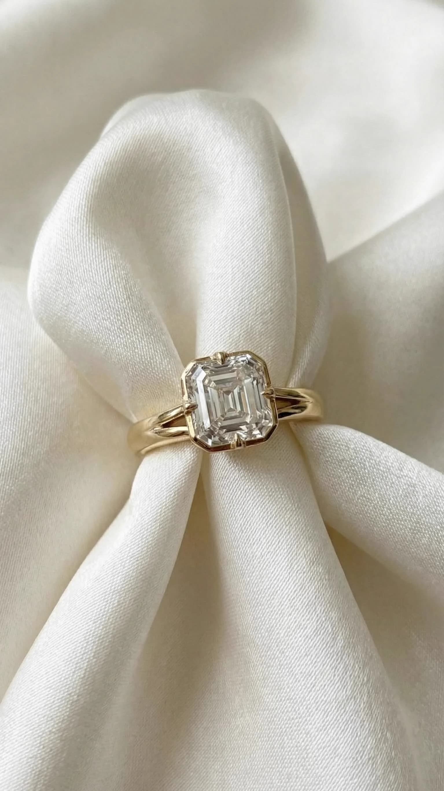 Asscher cut diamond engagement ring with a split shank in yellow gold, on ivory satin, by Lily Dia Jewellery